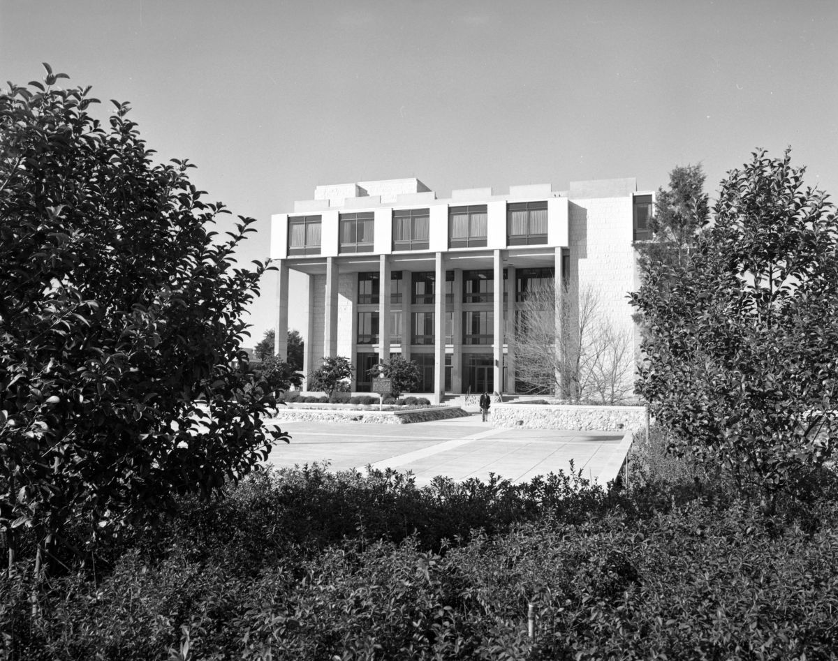 Modern building with a colonnade entrance and square windows under a clear sky.