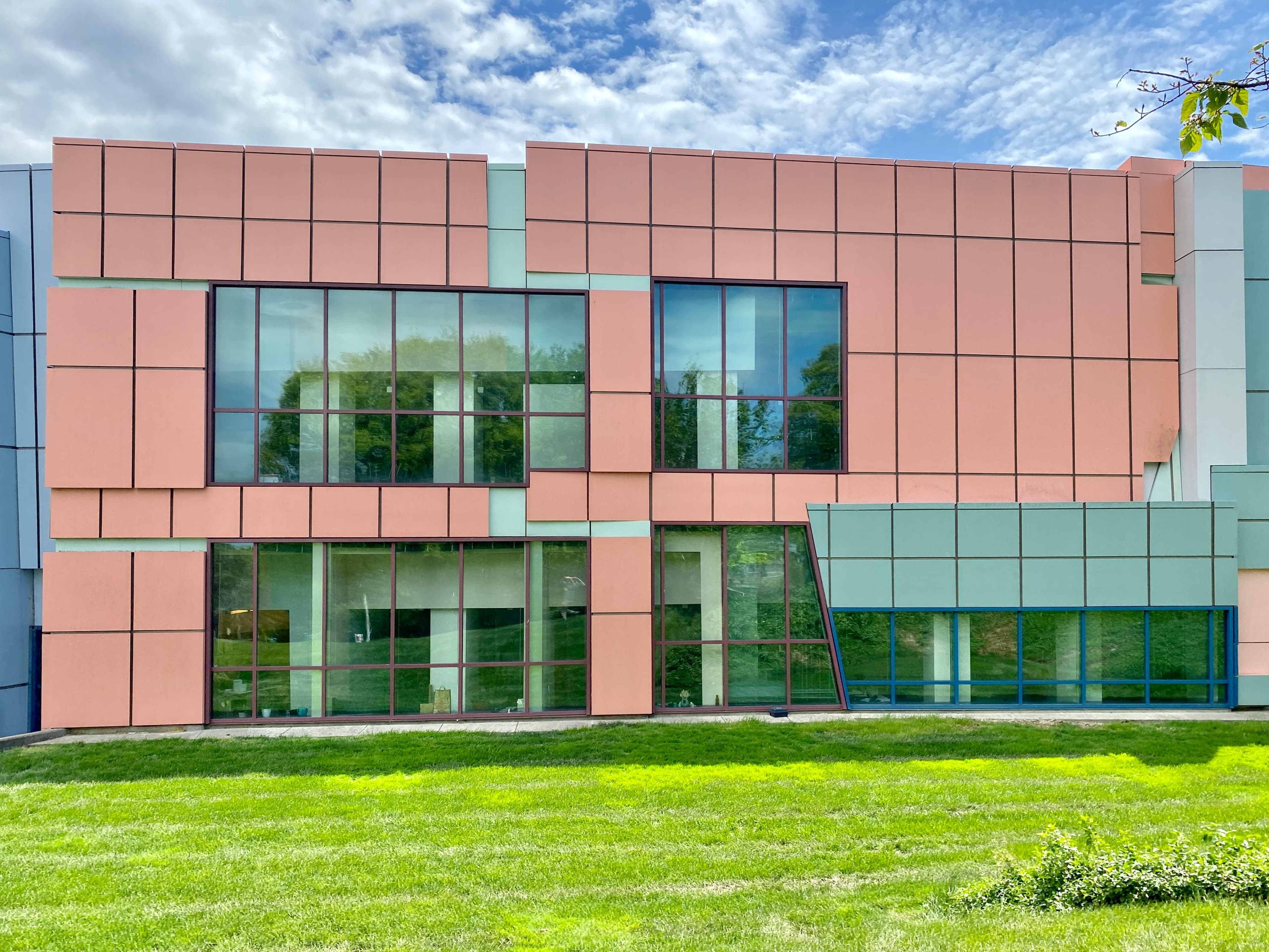 Modern building facade with pink and blue panels and large glass windows.