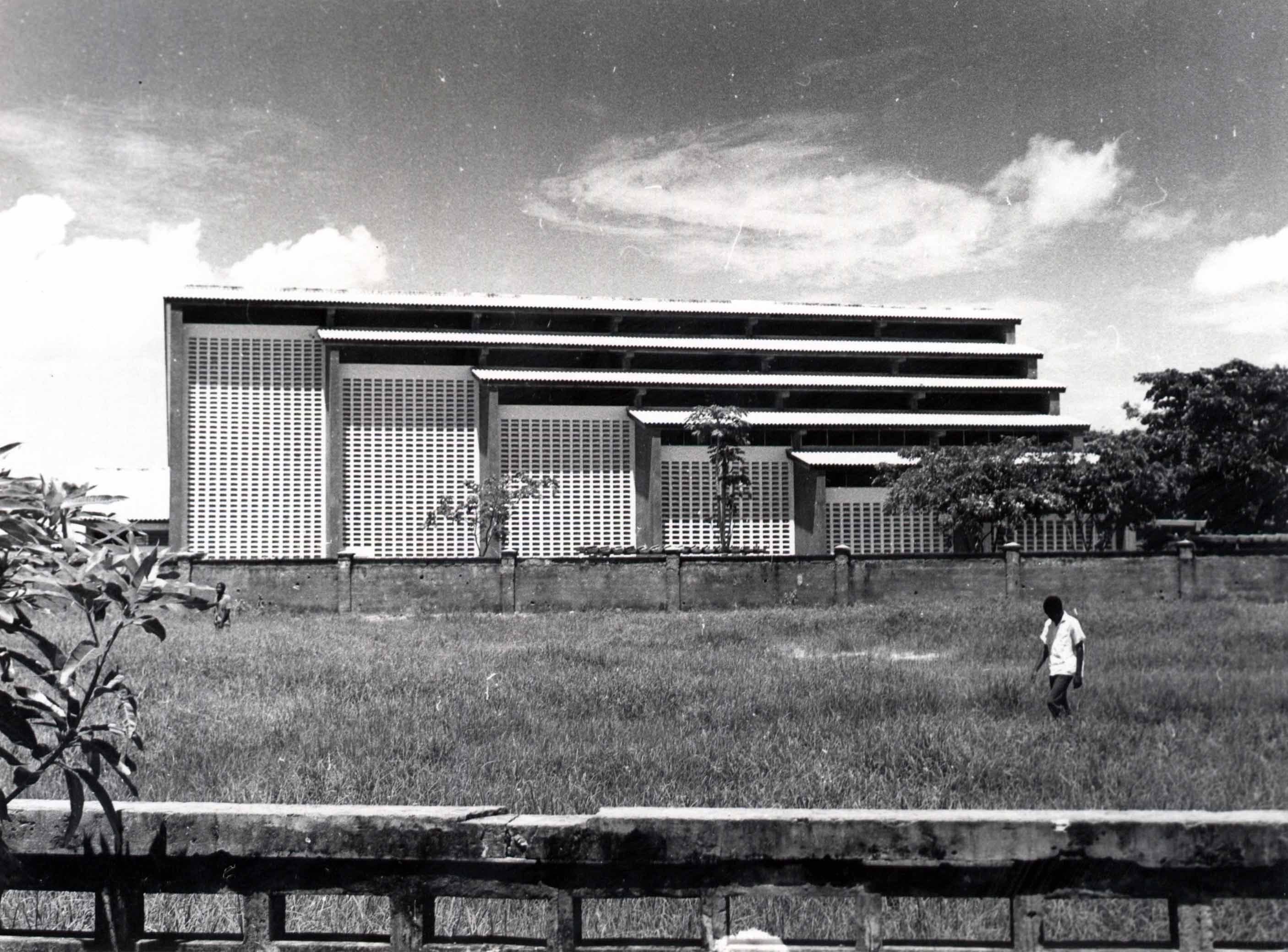 Wide shot of a multi-story modern building with horizontal bands under a cloudy sky.