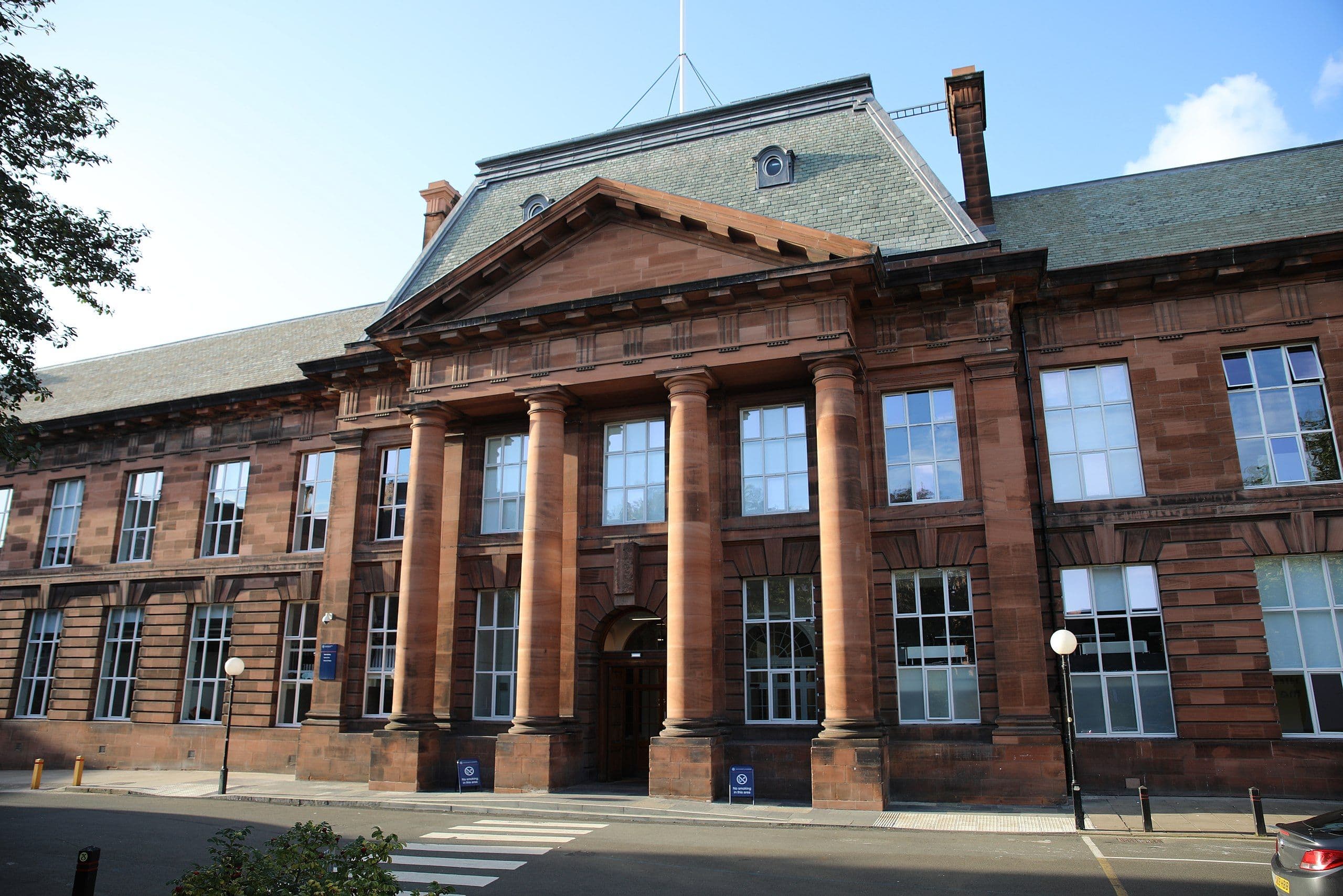 Red brick building with classical columns and a mansard roof under a blue sky.