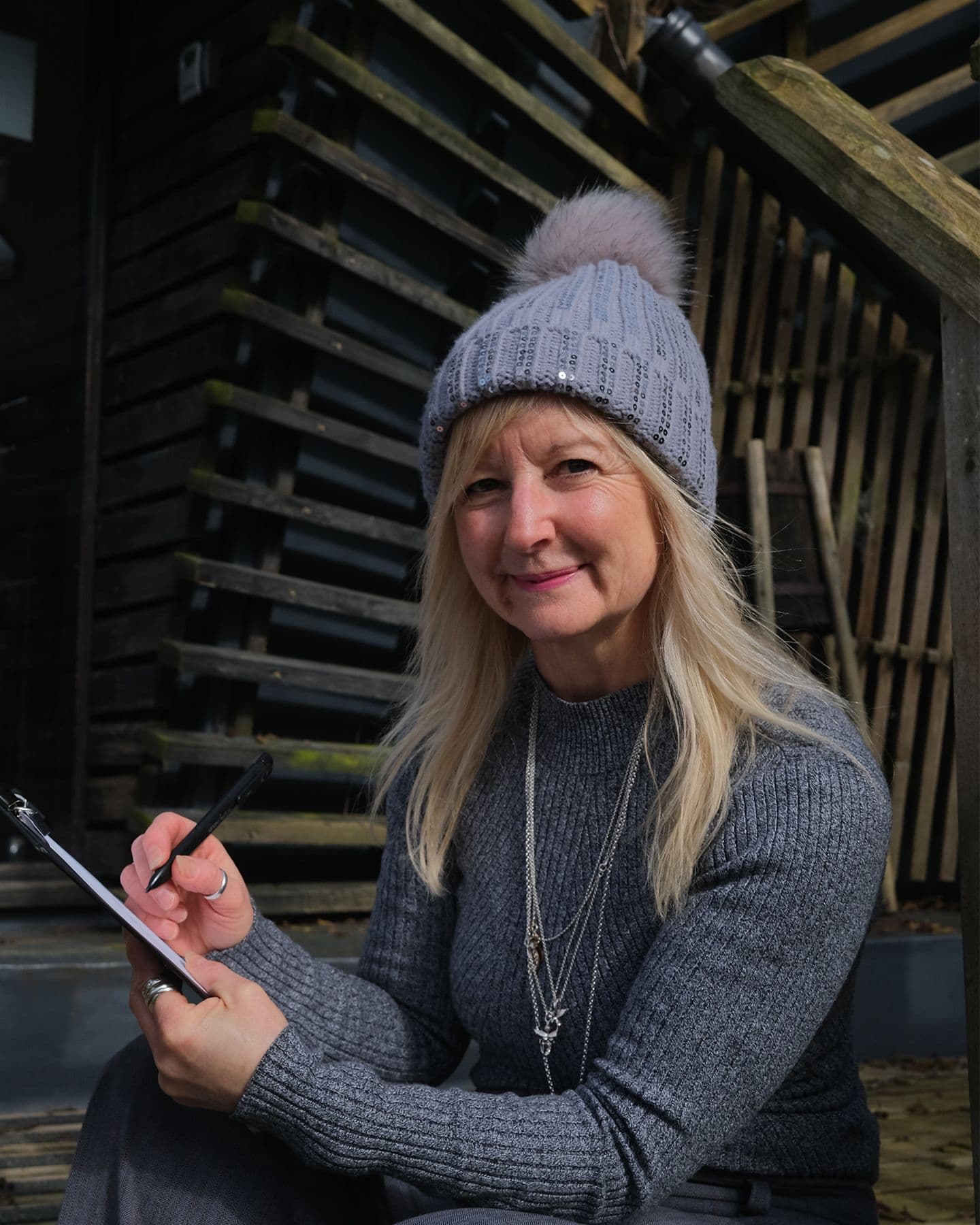 A white skinned woman with long blonde hair and wearing a bobble hat.