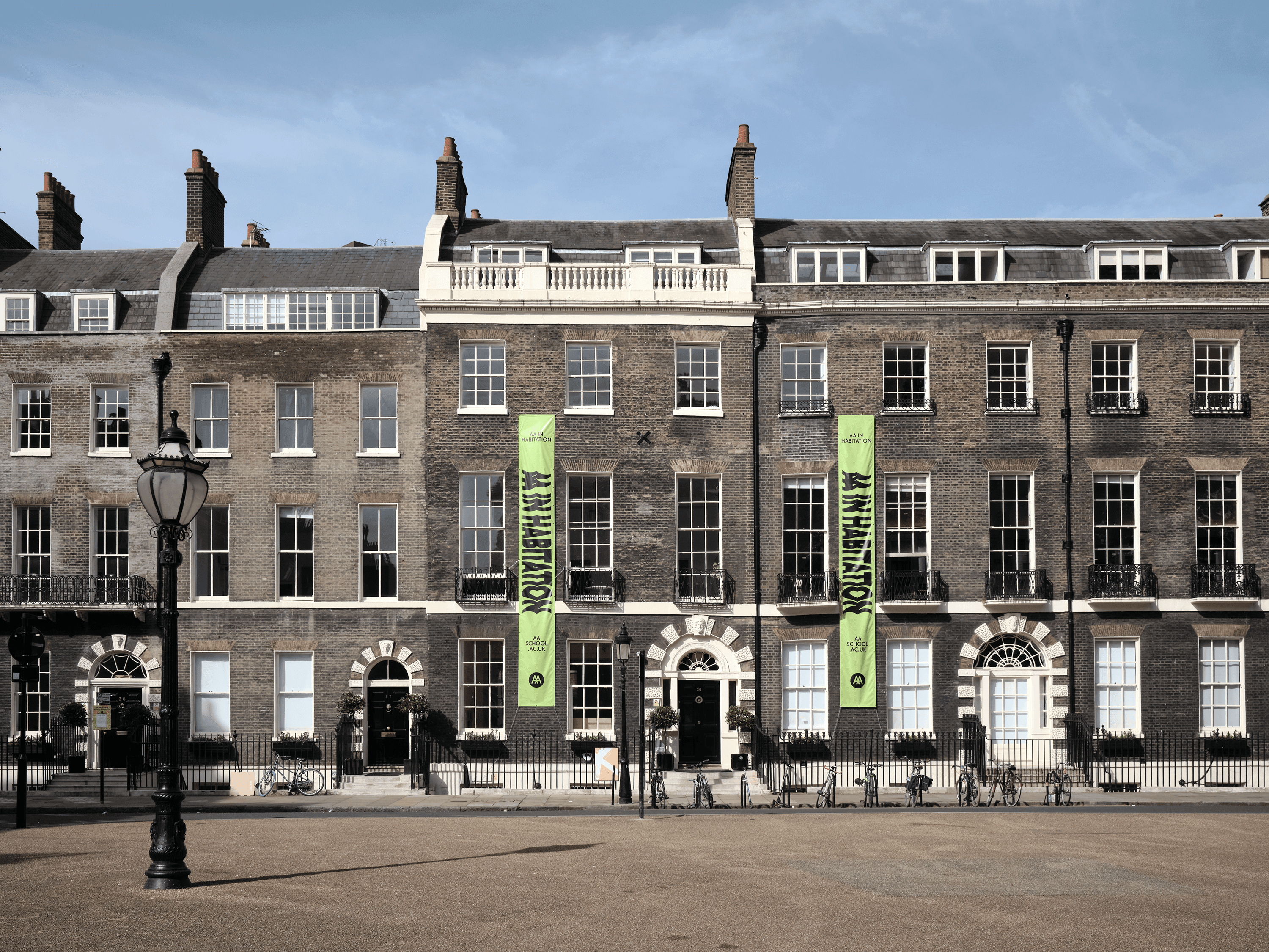 The Georgian façades of the AA buildings in Bedford Square, with green banners on the front of the buildings and the blue sky above.
