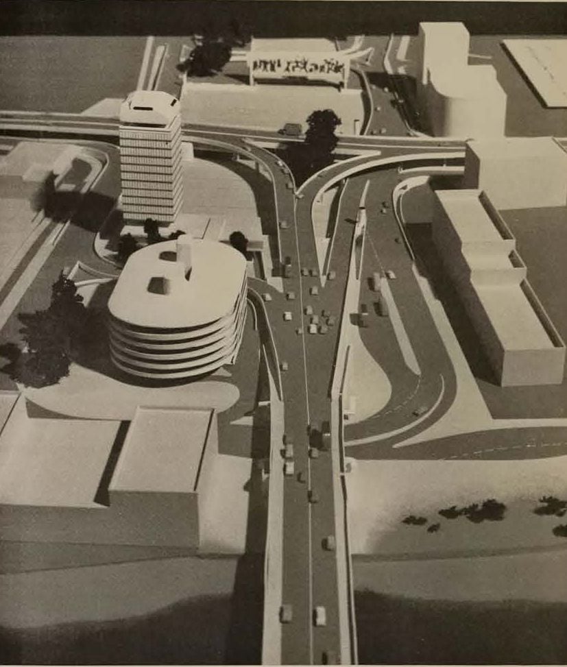 Miniature model depicting a multi-level highway interchange with surrounding buildings.