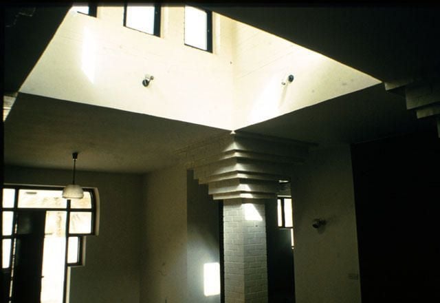 Modern architectural interior featuring a square ceiling light well and a layered geometric column.