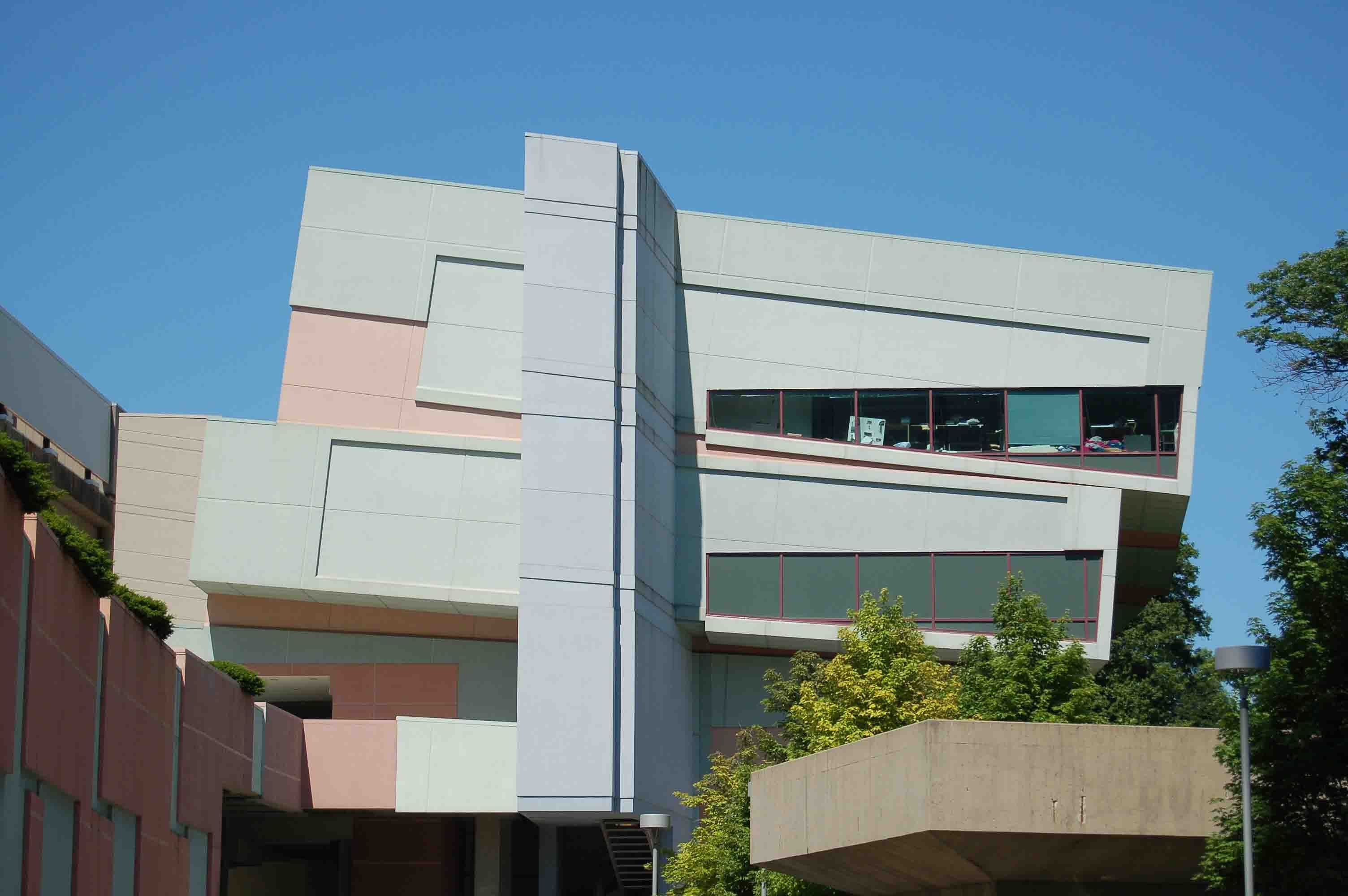 Modern building with geometric shapes and pastel-colored panels under a clear blue sky.