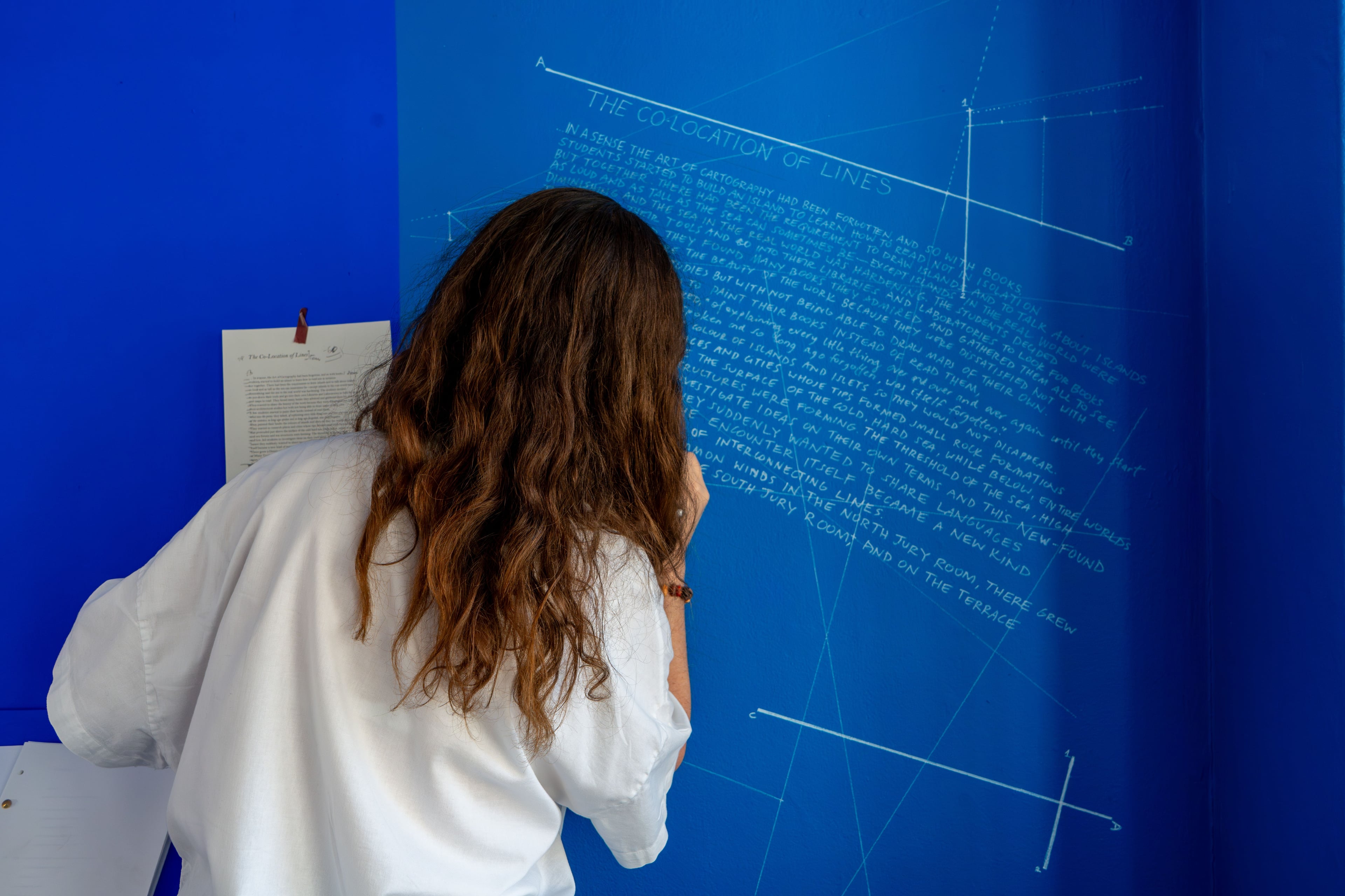 A person writing on a blue wall