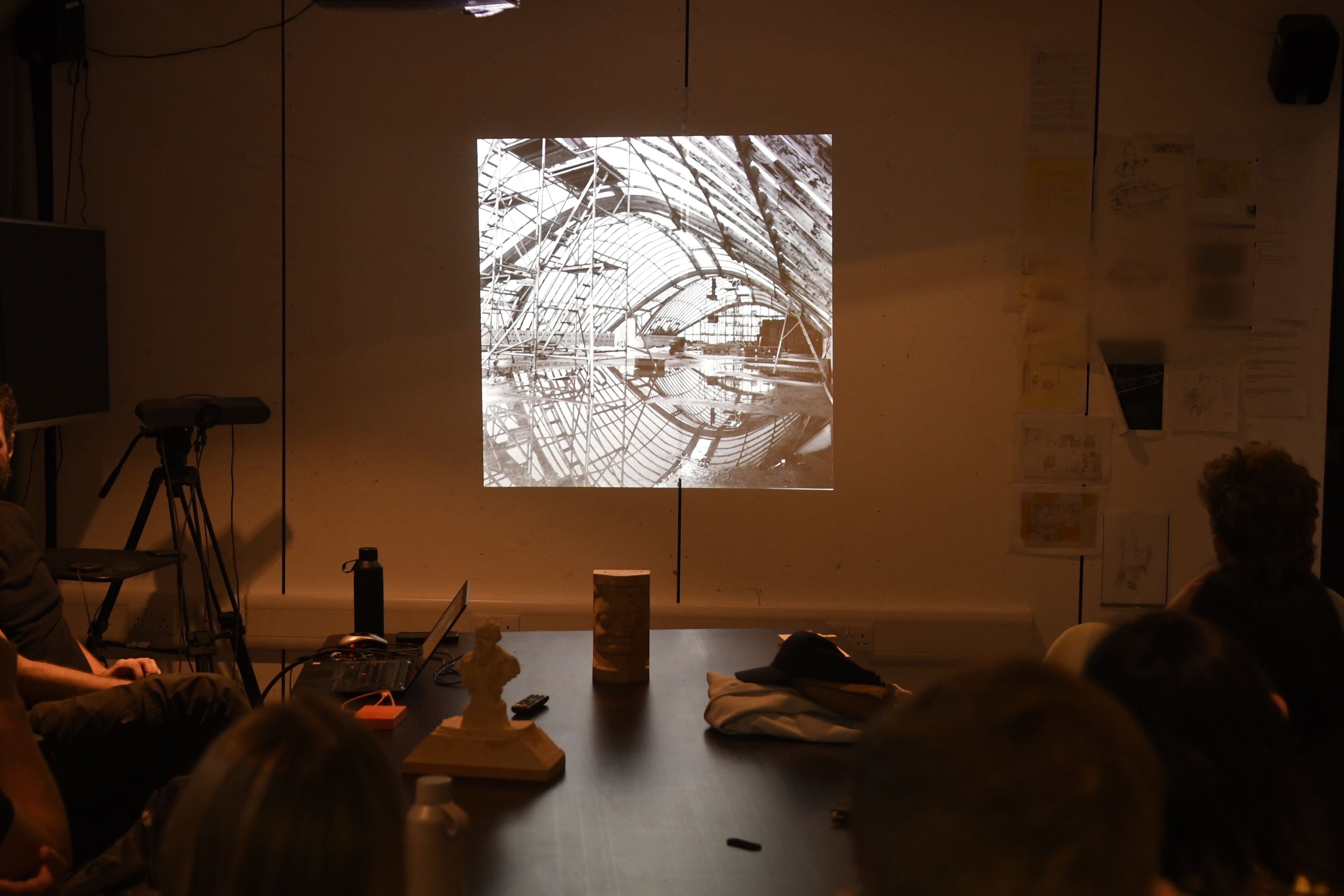 A photo of a building under construction is projected onto a white wall in a dark room.