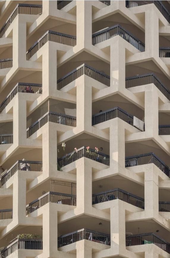 Modern building facade with interlocking geometric concrete patterns and balconies.