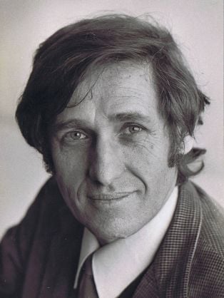 Black and white portrait of a man with dark hair, wearing a collared shirt and tie.