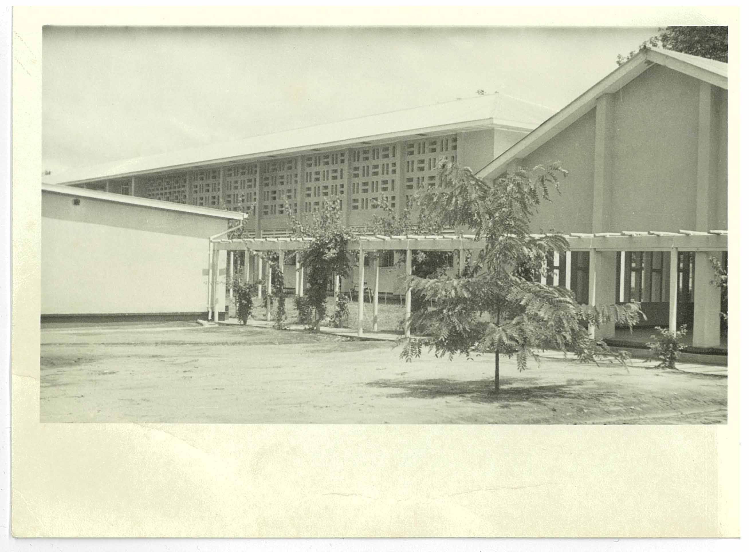 Exterior view of a modern building with a long, covered walkway and decorative screen.