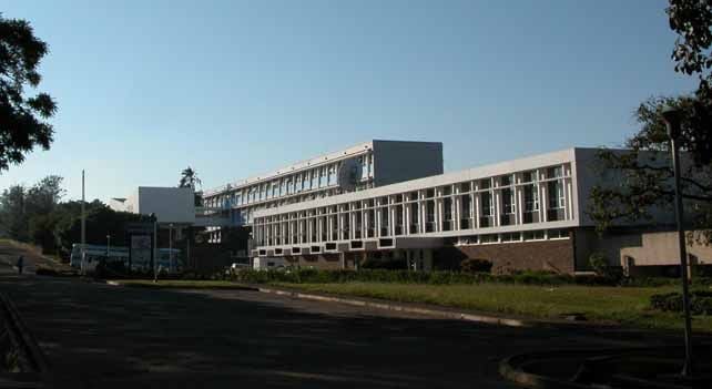 Modernist university building with rows of windows and a clear blue sky above.