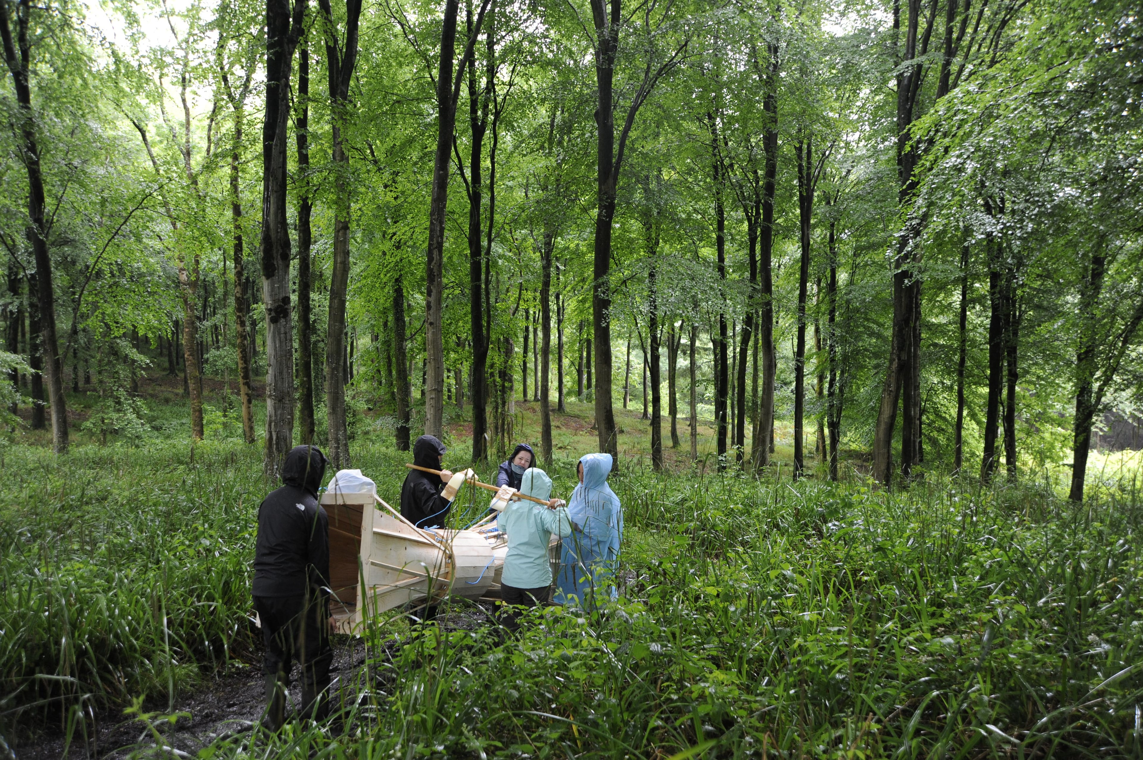 A group of students carrier a large-scale work through the Hooke Park forest in Dorset