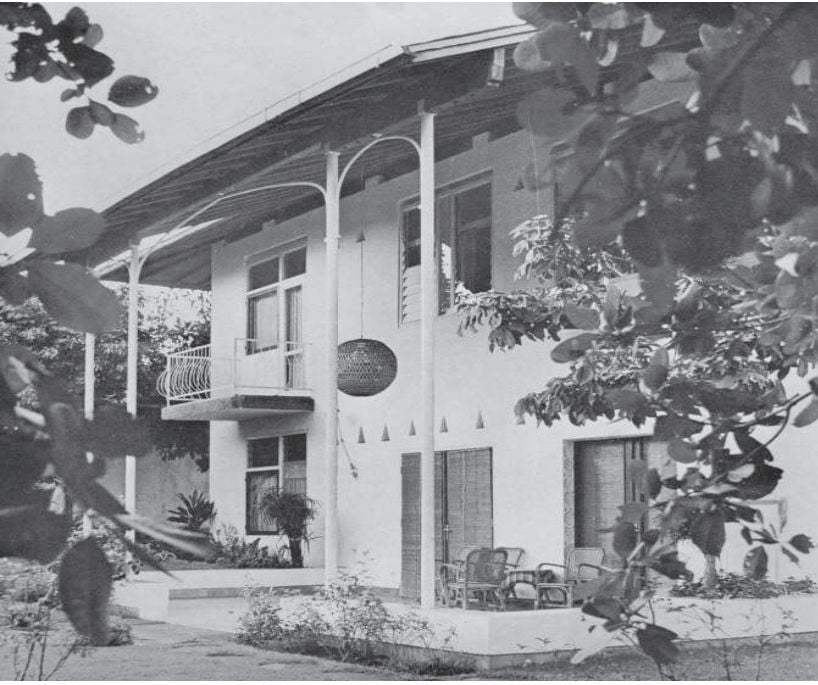 A white two-story house with a wrap-around porch and decorative columns.